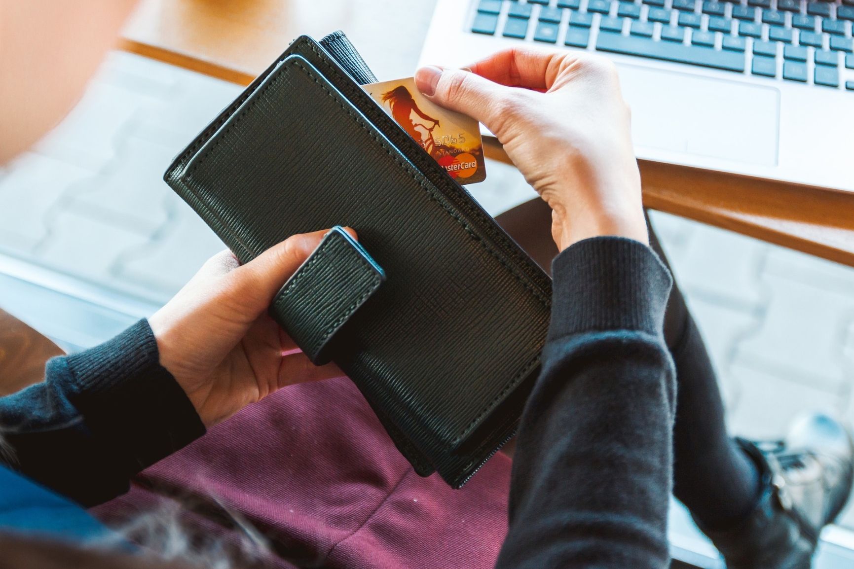 Kvinna med plånbok framför dator
