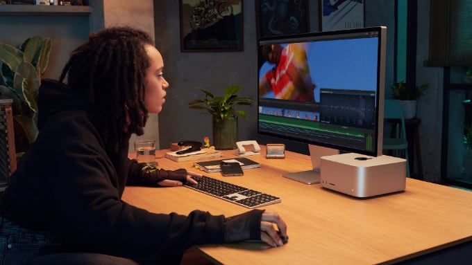 Kvinna sitter vid Mac Studio med Studio Display