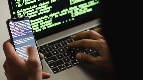 Hackare med laptop och mobil